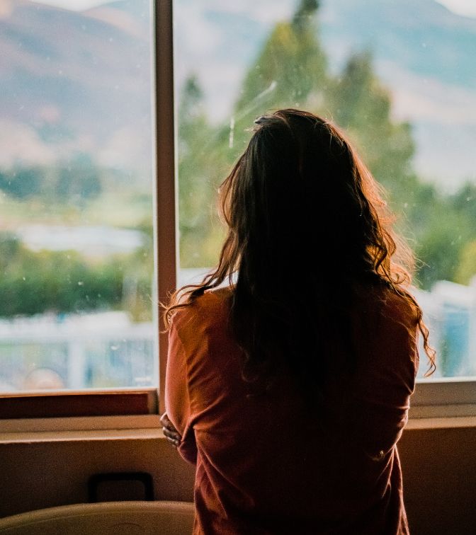 A woman standing looking out of the window