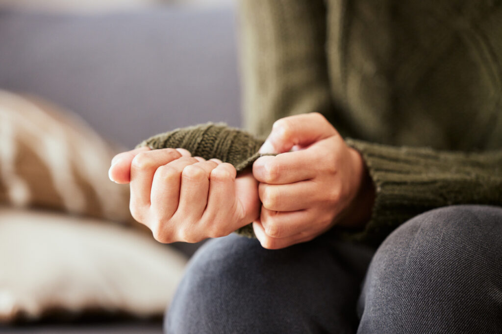 Image of a woman's hands who is sitting on a sofa and feeling anxious