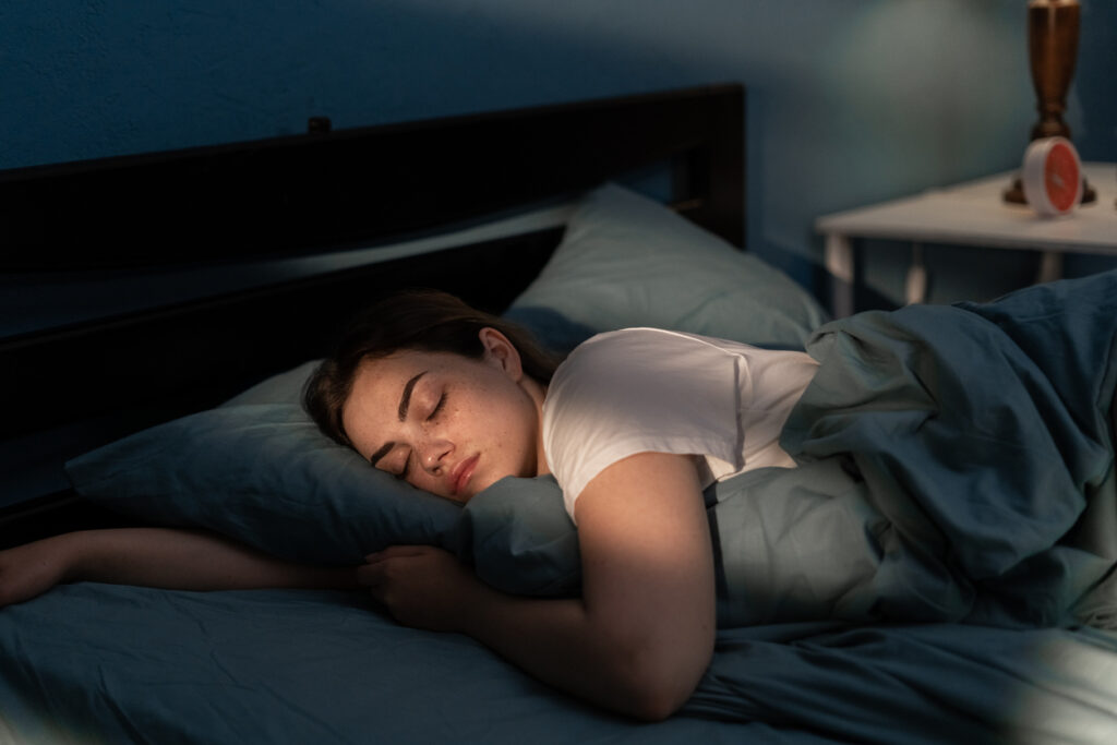 Young female sleeping peacefully in her bedroom at night