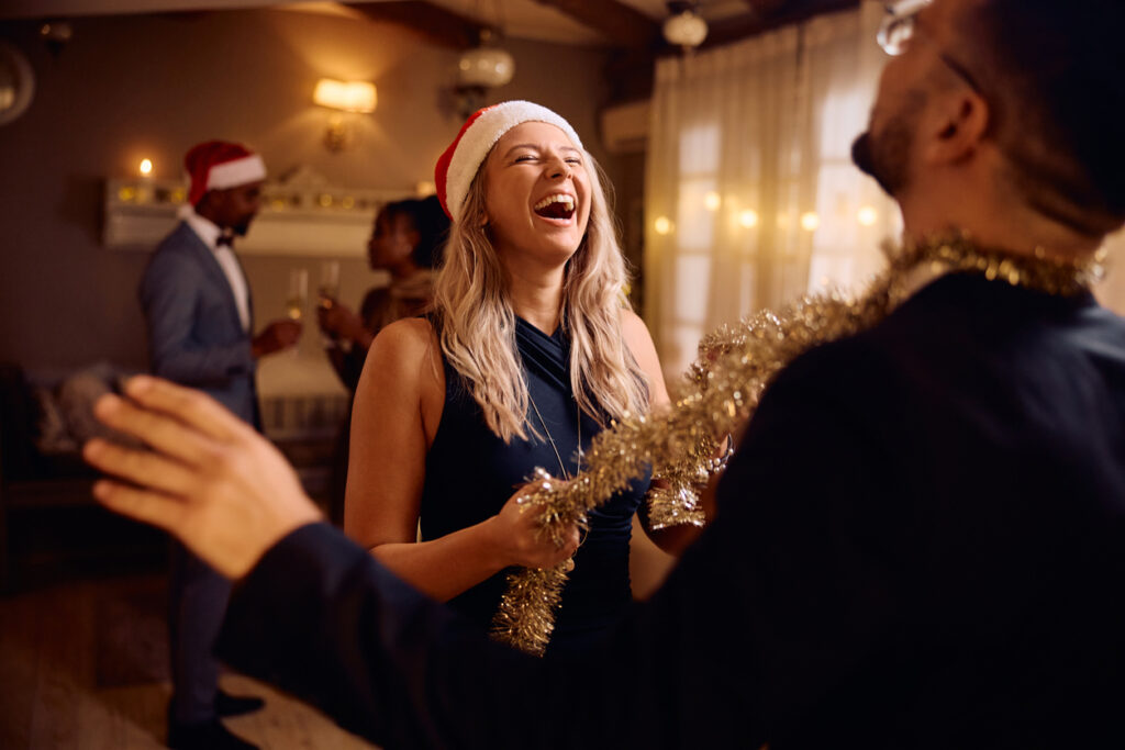 Young woman laughing while dancing with her boyfriends on Christmas party.